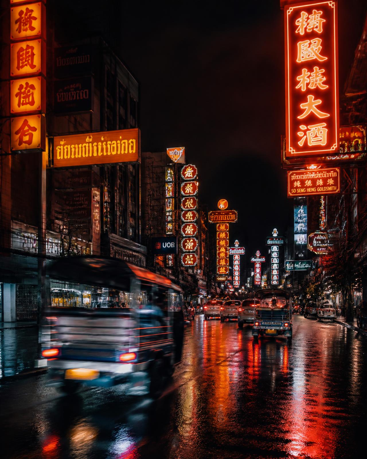 Neon-lit Bangkok street at night with a tuk tuk passing